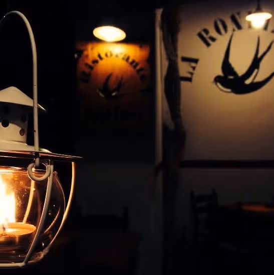 Interior of La Rondinella osteria in Scalea, with a lantern and the swallow logo.